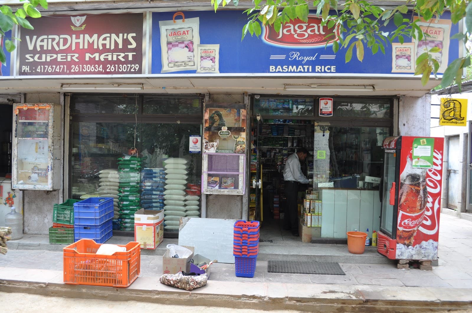 A kirana store: sacks of basmati rice stacked behind the glass, crates on the pavement